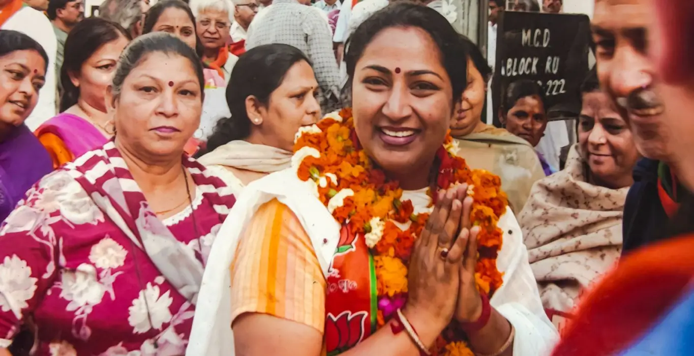 Rekha Gupta wearing marigold garlands and greeting supporters with folded hands