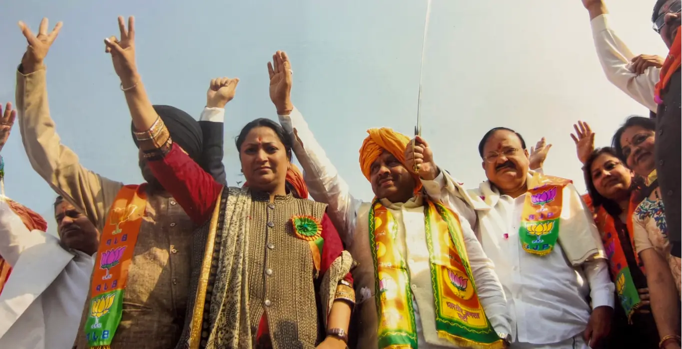 Rekha Gupta raising a victory sign alongside fellow leaders at an outdoor rally