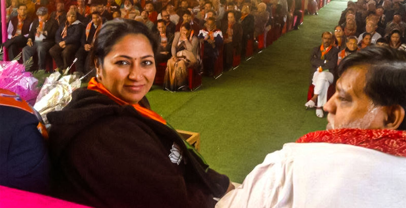 Rekha Gupta seated on stage at a BJP public meeting