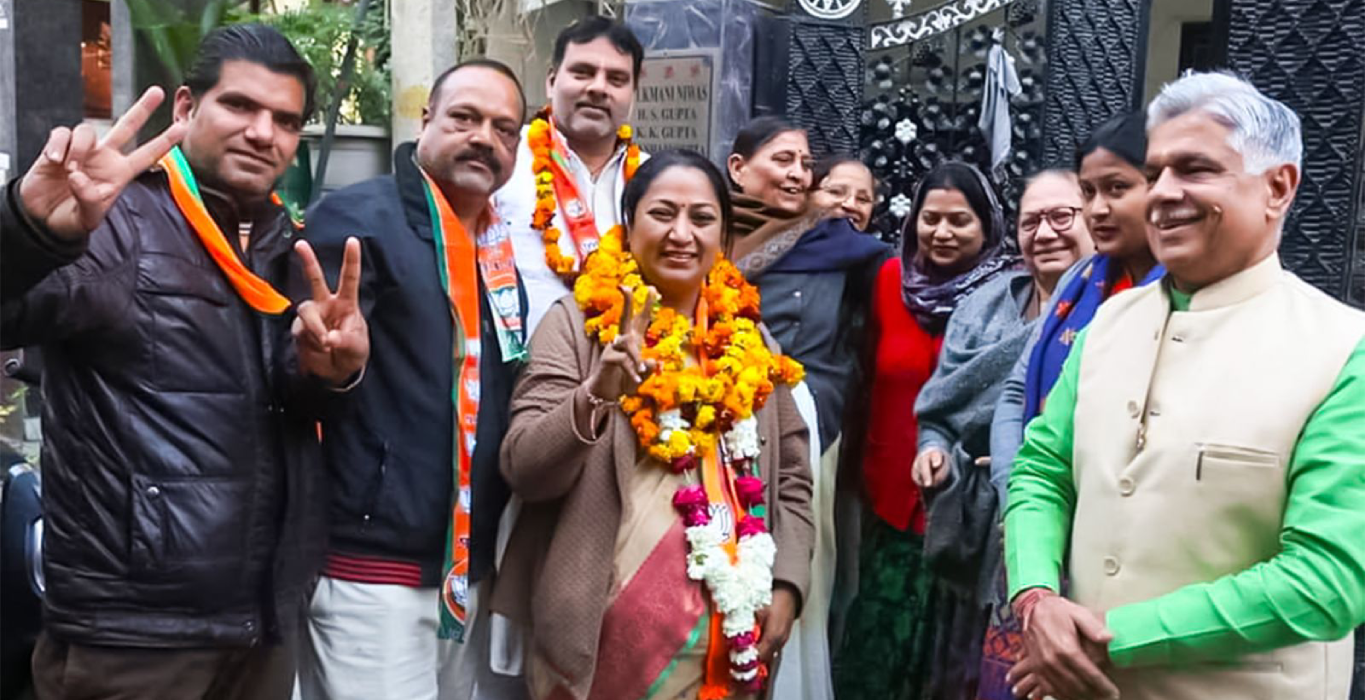 Rekha Gupta wearing flower garlands and showing a victory sign with supporters