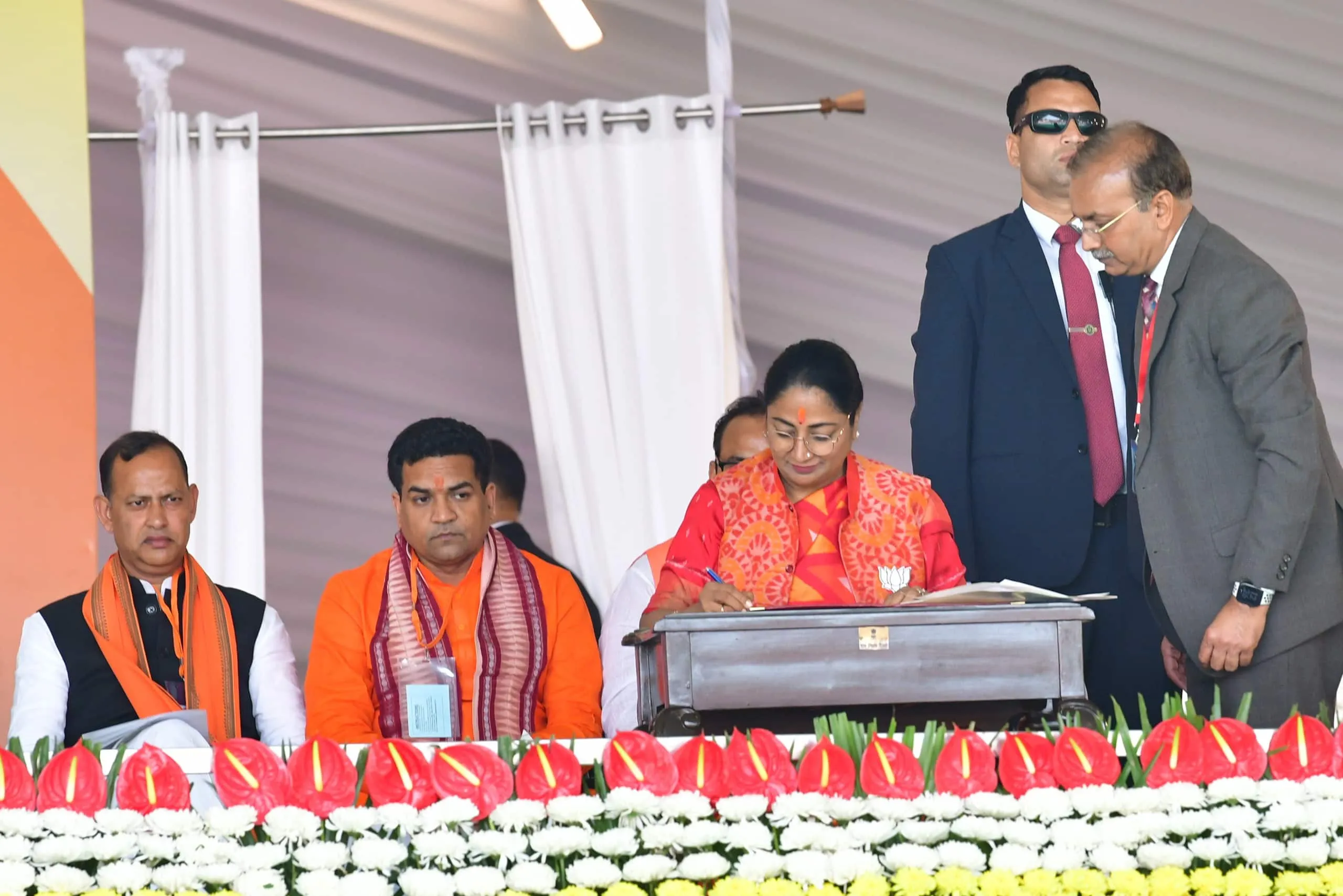 Delhi CM Rekha Gupta signing a document on stage during an official ceremony